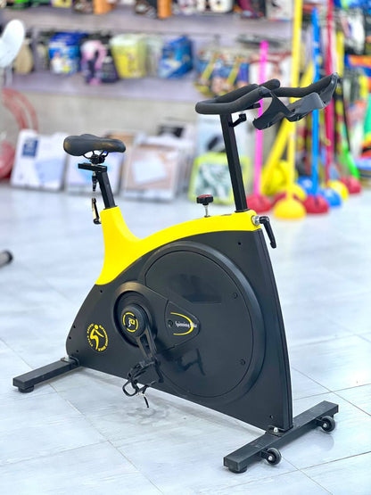 دراجة تمارين داخلية (Spinning Bike) باللونين الأصفر والأسود.